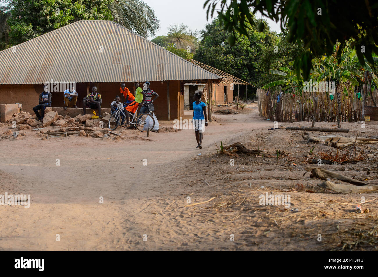 OUSSOUYE, SENEGAL - Apr 30, 2017: Non identificato donna senegalese in maglietta blu e mantello colorato cammina lungo la strada nel bosco sacro vicino Kaguit Foto Stock