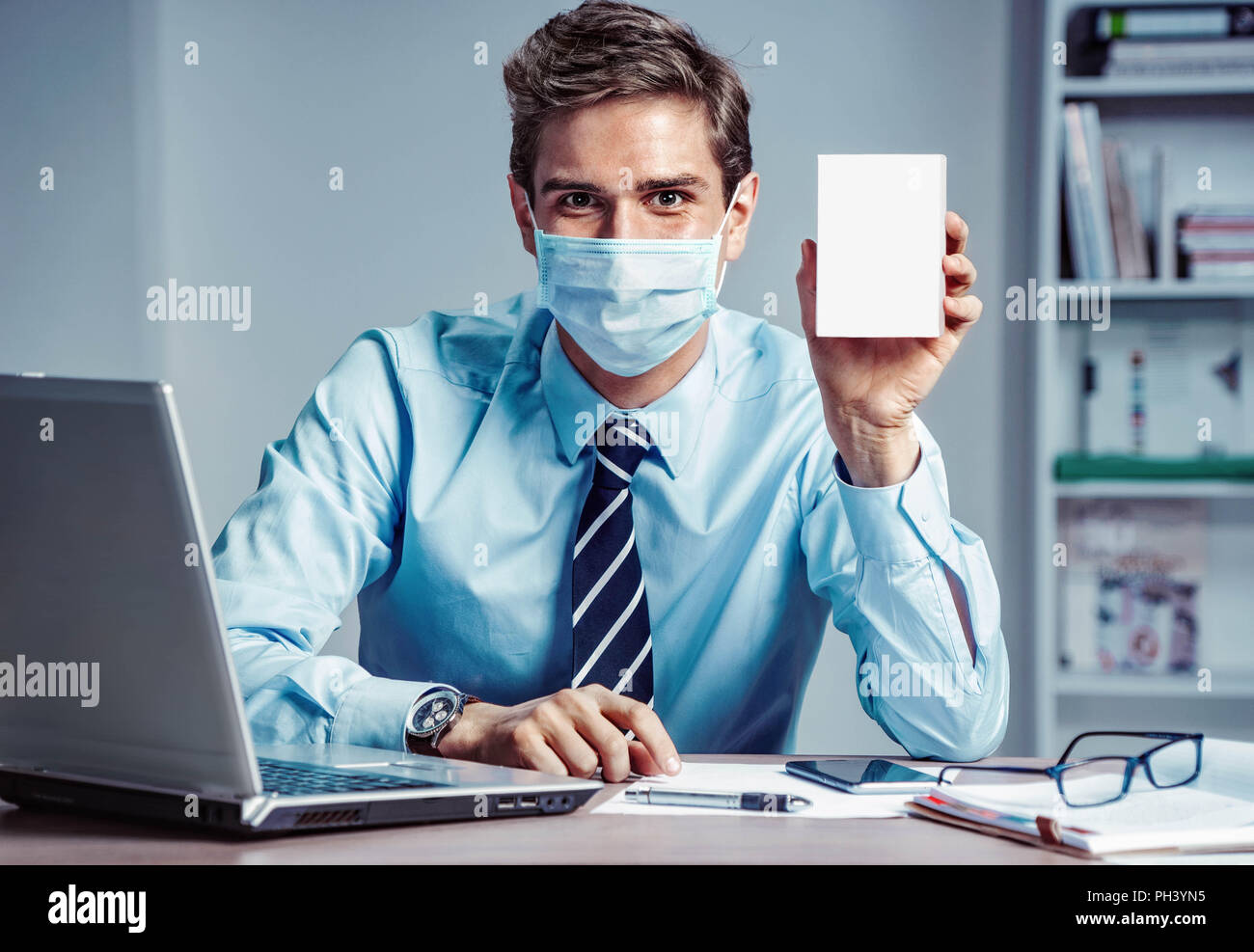 Lavoratore sano in ufficio azienda casella bianca della medicina. Foto di un uomo che indossa la maschera di protezione contro le malattie infettive e l'influenza. Business e hea Foto Stock