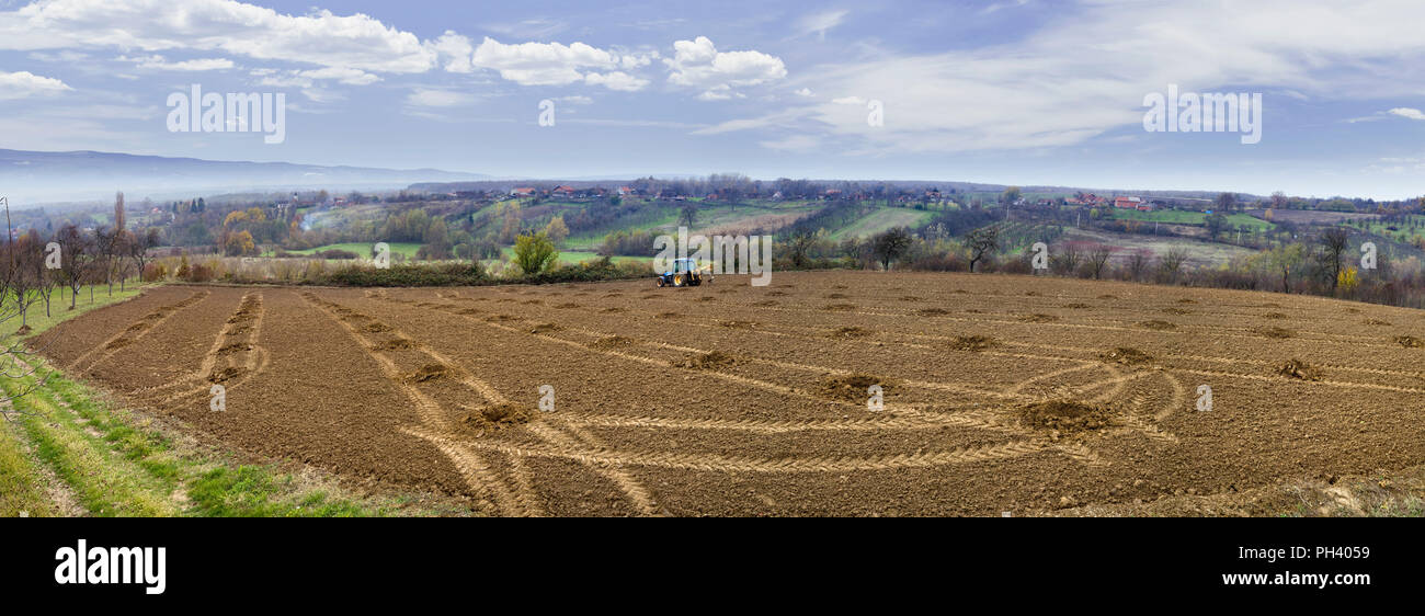 Scavare buche nel frutteto con il trattore Foto Stock