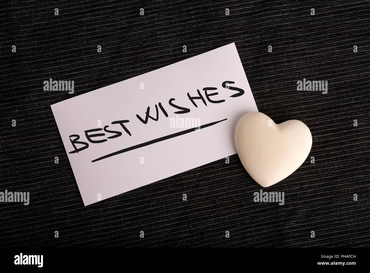 I migliori auguri per una persona amata con una scritta a mano normale carta bianca dicendo - I migliori Auguri - con una crema cuore su uno sfondo nero, vie aeree Foto Stock