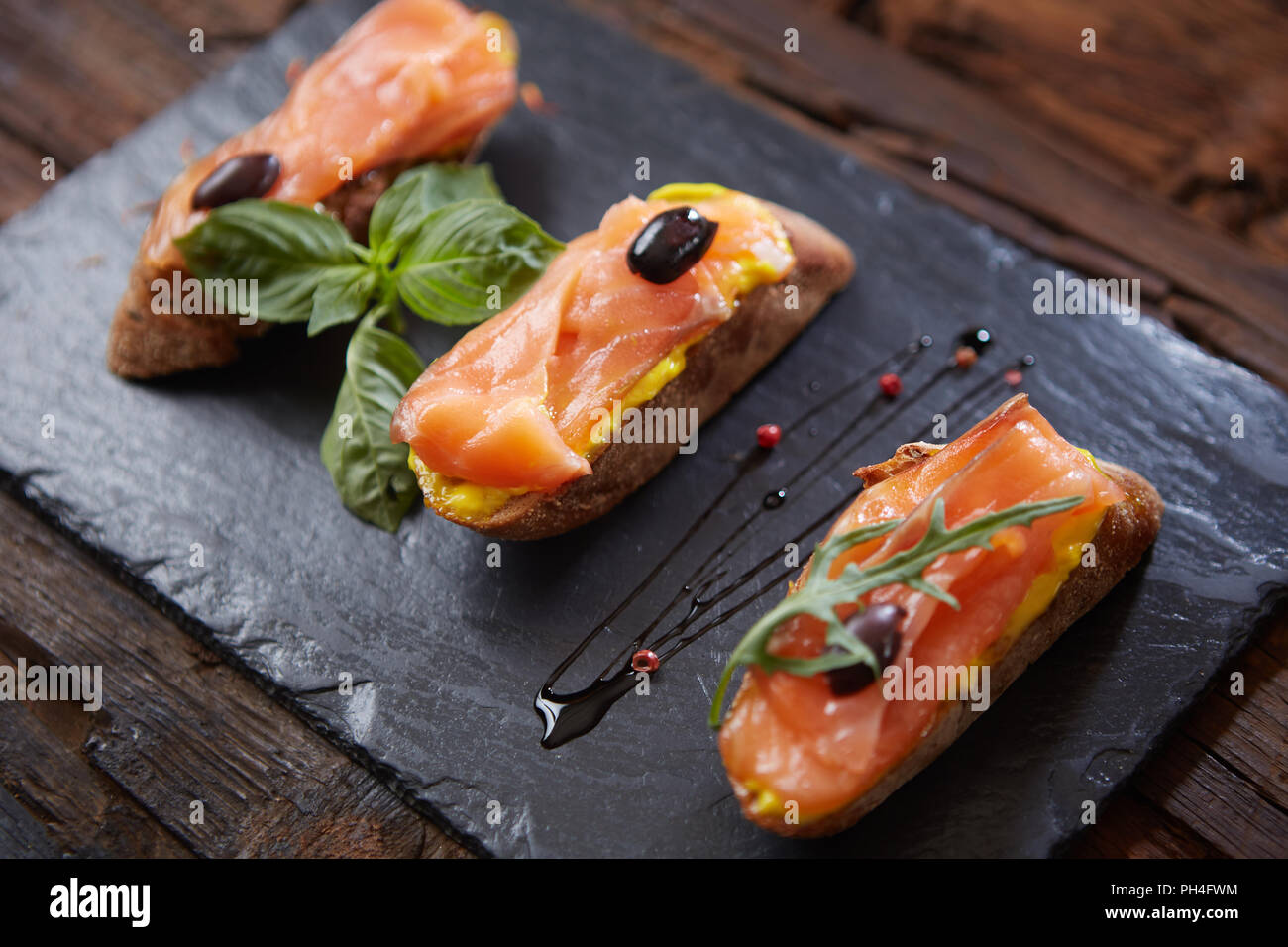 Le gustose bruschette con salmone su pietra nera Foto Stock