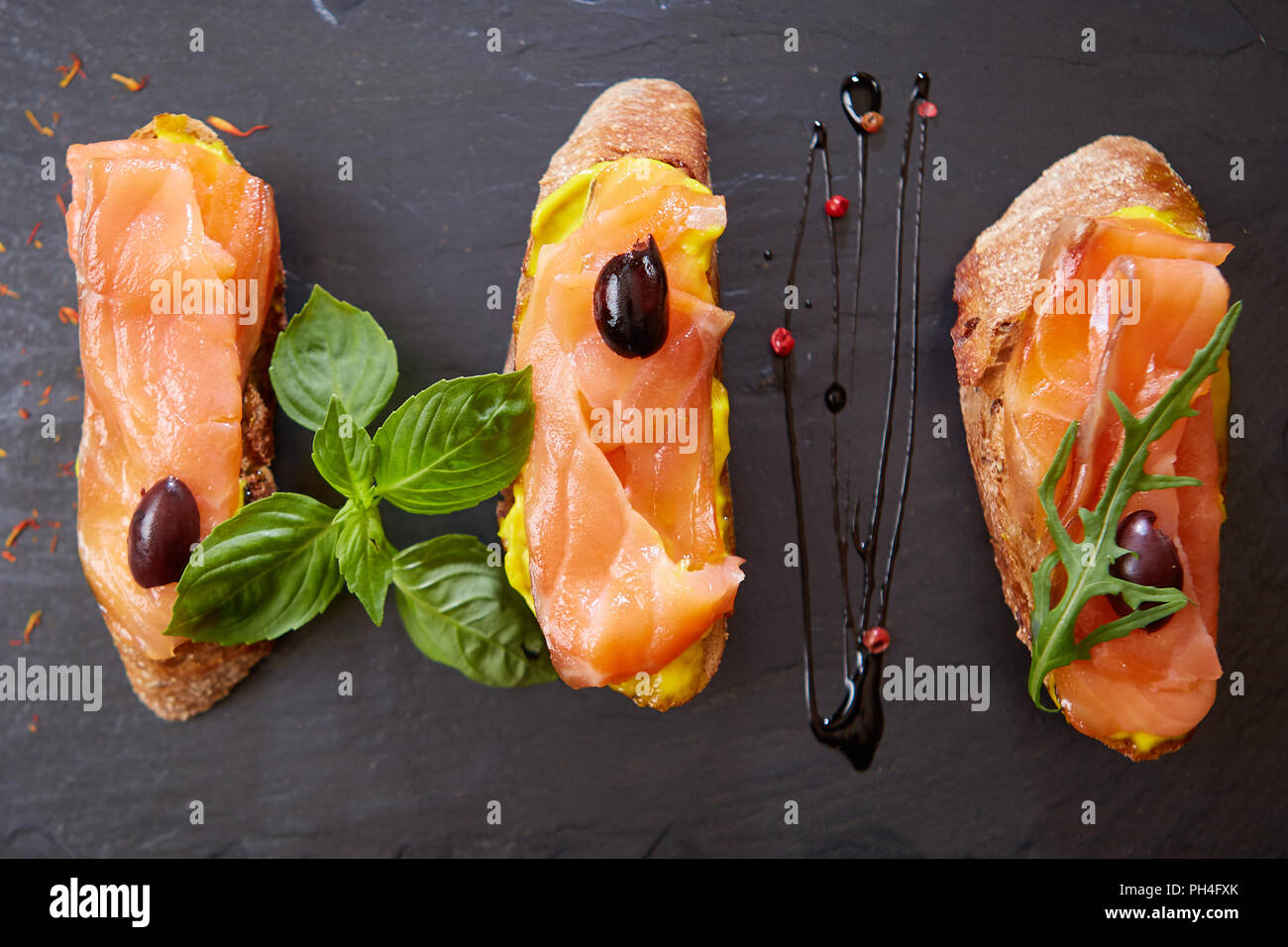 Le gustose bruschette con salmone su pietra nera Foto Stock