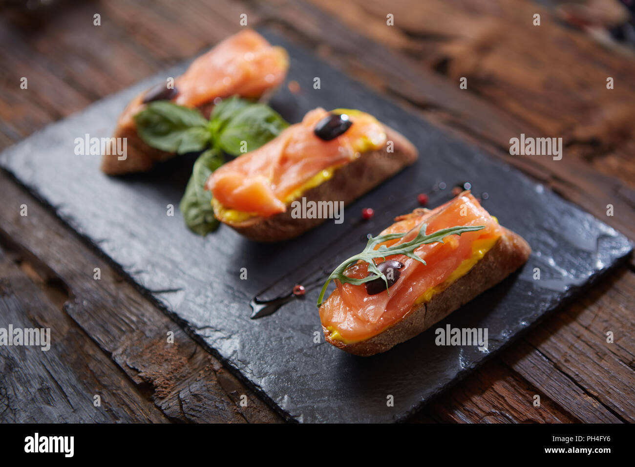 Le gustose bruschette con salmone su pietra nera Foto Stock