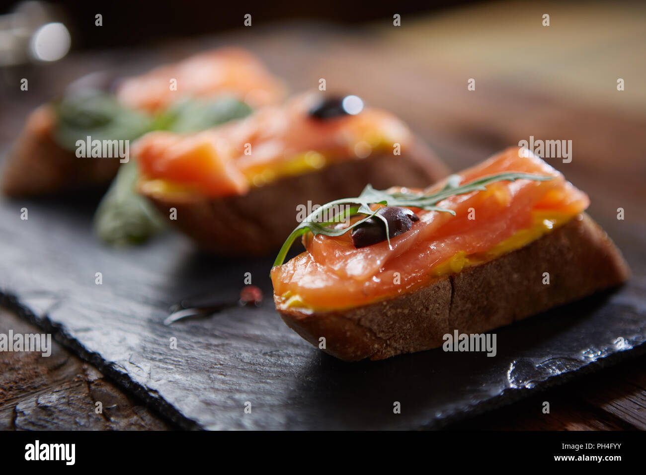 Le gustose bruschette con salmone su pietra nera Foto Stock