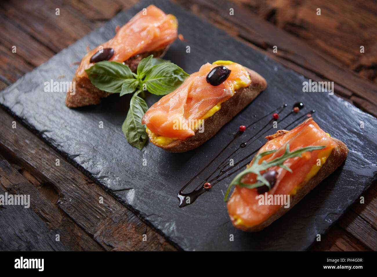 Le gustose bruschette con salmone su pietra nera Foto Stock
