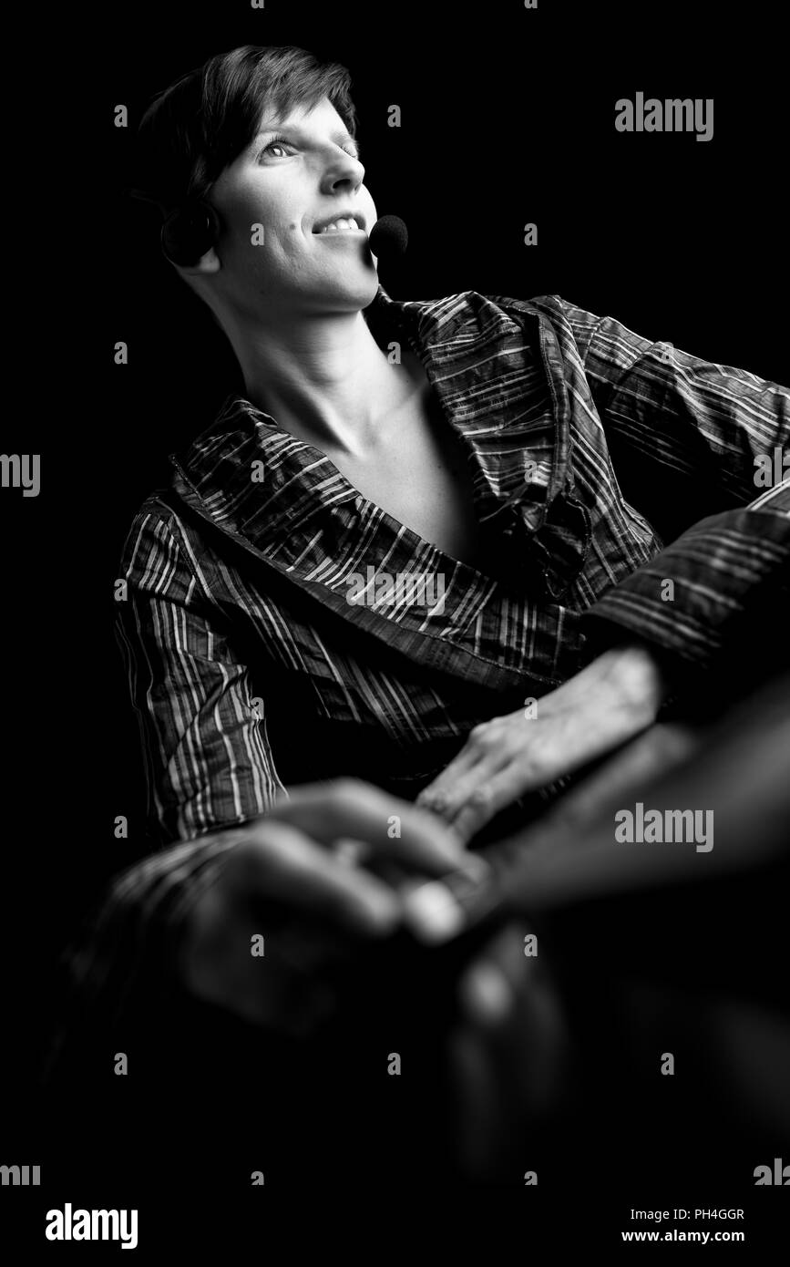 Angolo basso in bianco e nero ritratto di una giovane donna attraente di indossare una cuffia di sorridere quando lei ascolta la conversazione concettuale del un call centr Foto Stock