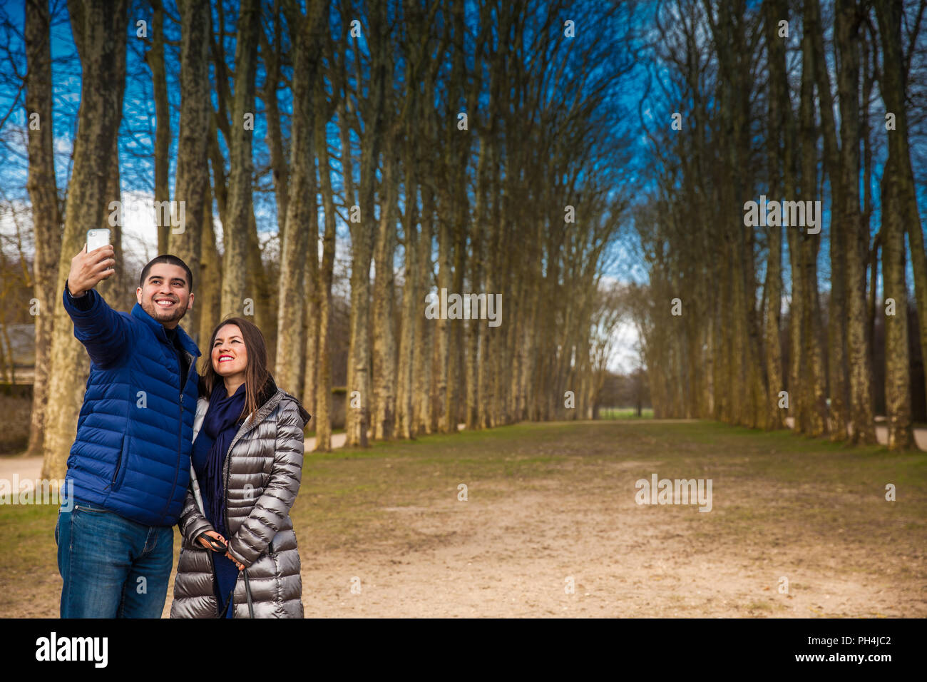 Coppia di turisti prendendo un selfie presso il giardino del Palazzo di Versailles in un gelido inverno giorno appena prima della primavera Foto Stock