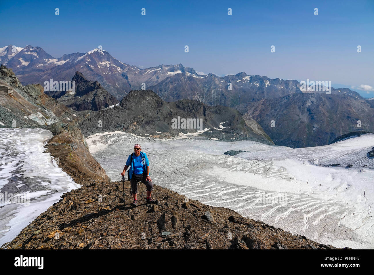 Femmina solitario escursionista sopra Saas Fee, a Mittelallalin comprensorio sciistico estivo, Saastal, Svizzera Foto Stock