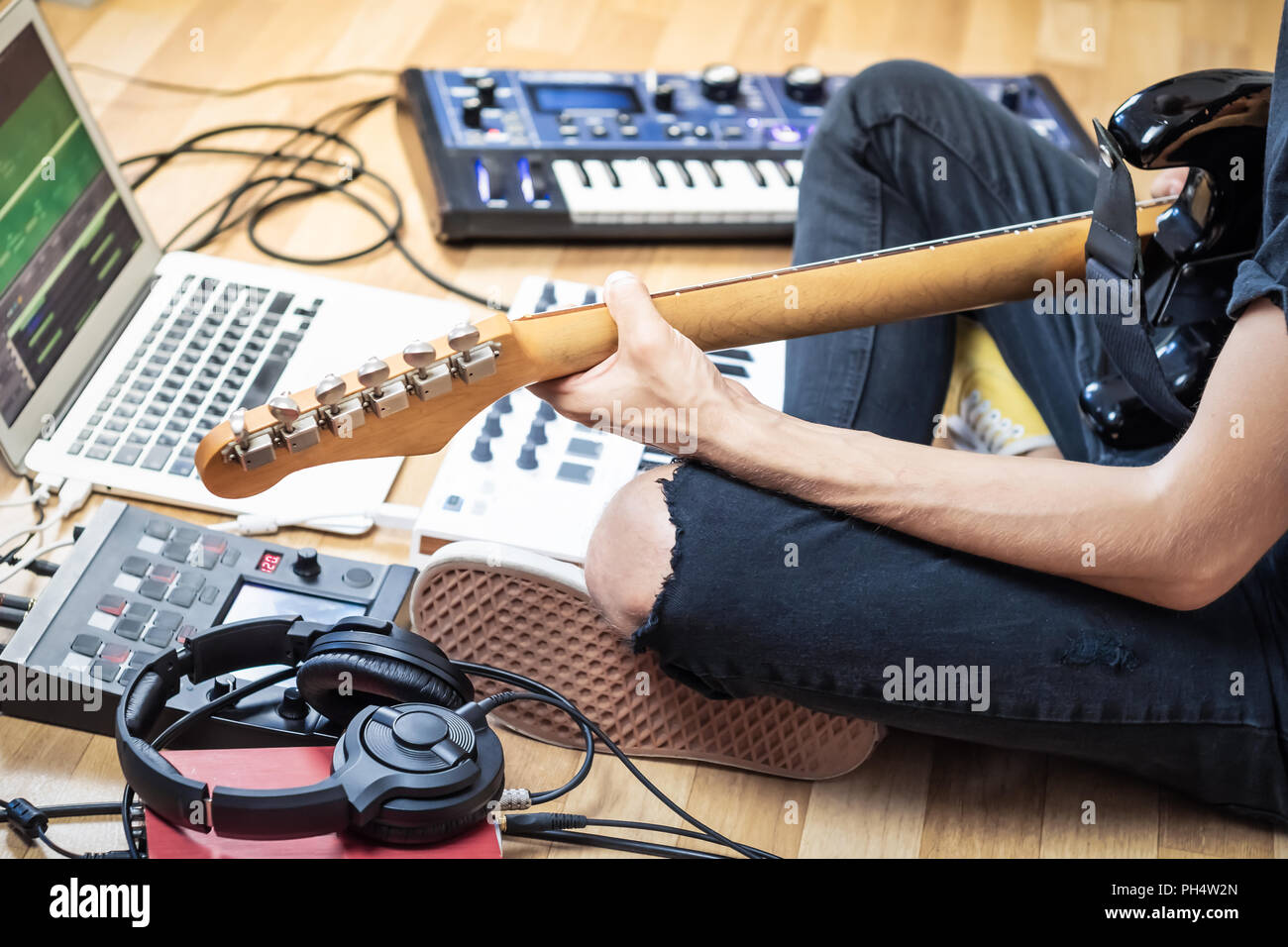 Chitarrista maschio di suonare una chitarra elettrica a casa moderna in studio o in sala prove. Giovane di produrre musica con effetti elettronici processori, synthesi Foto Stock