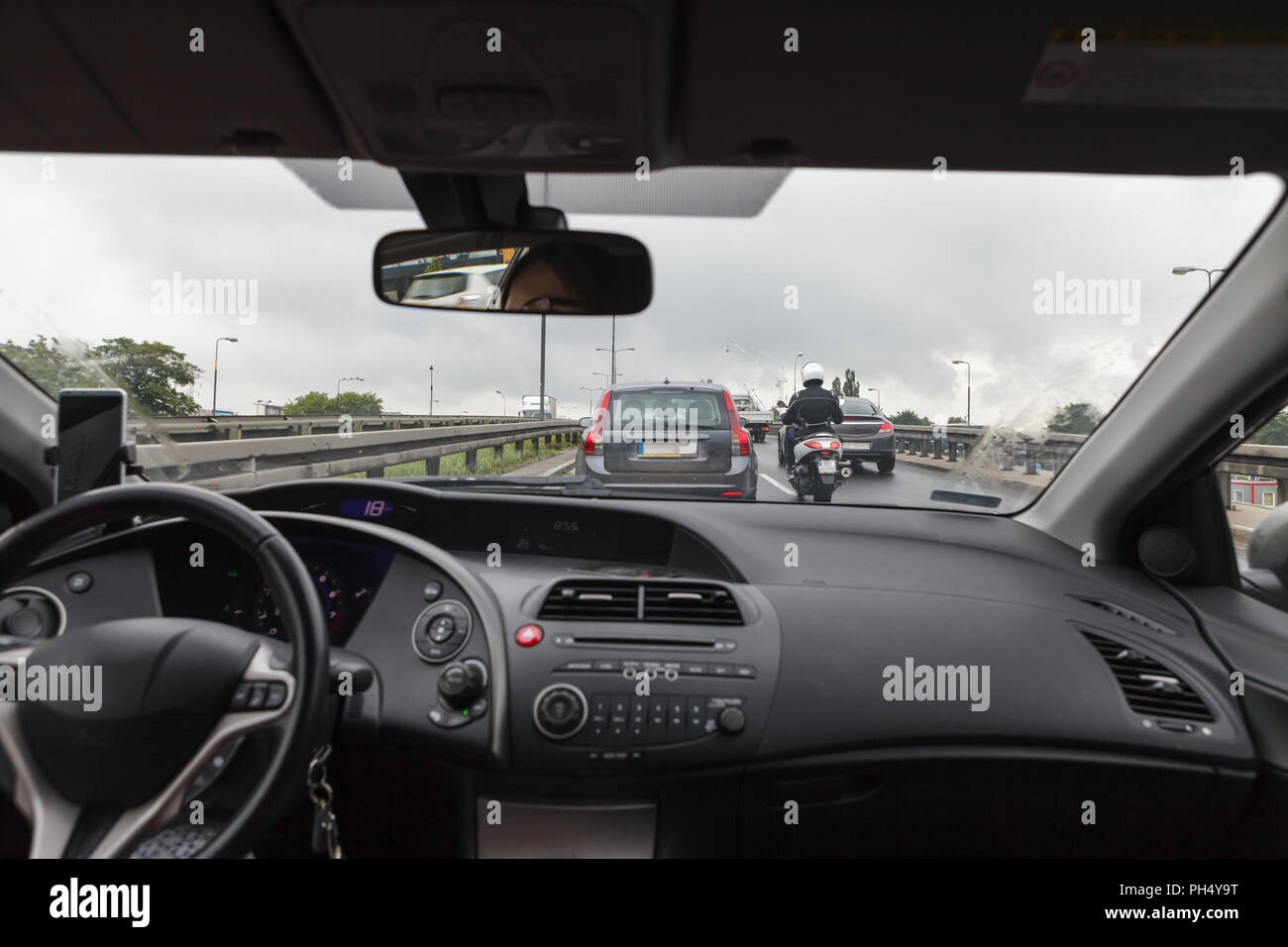 Alla guida di una autovettura in un ingorgo, vista dall'interno sulla strada affollata Foto Stock