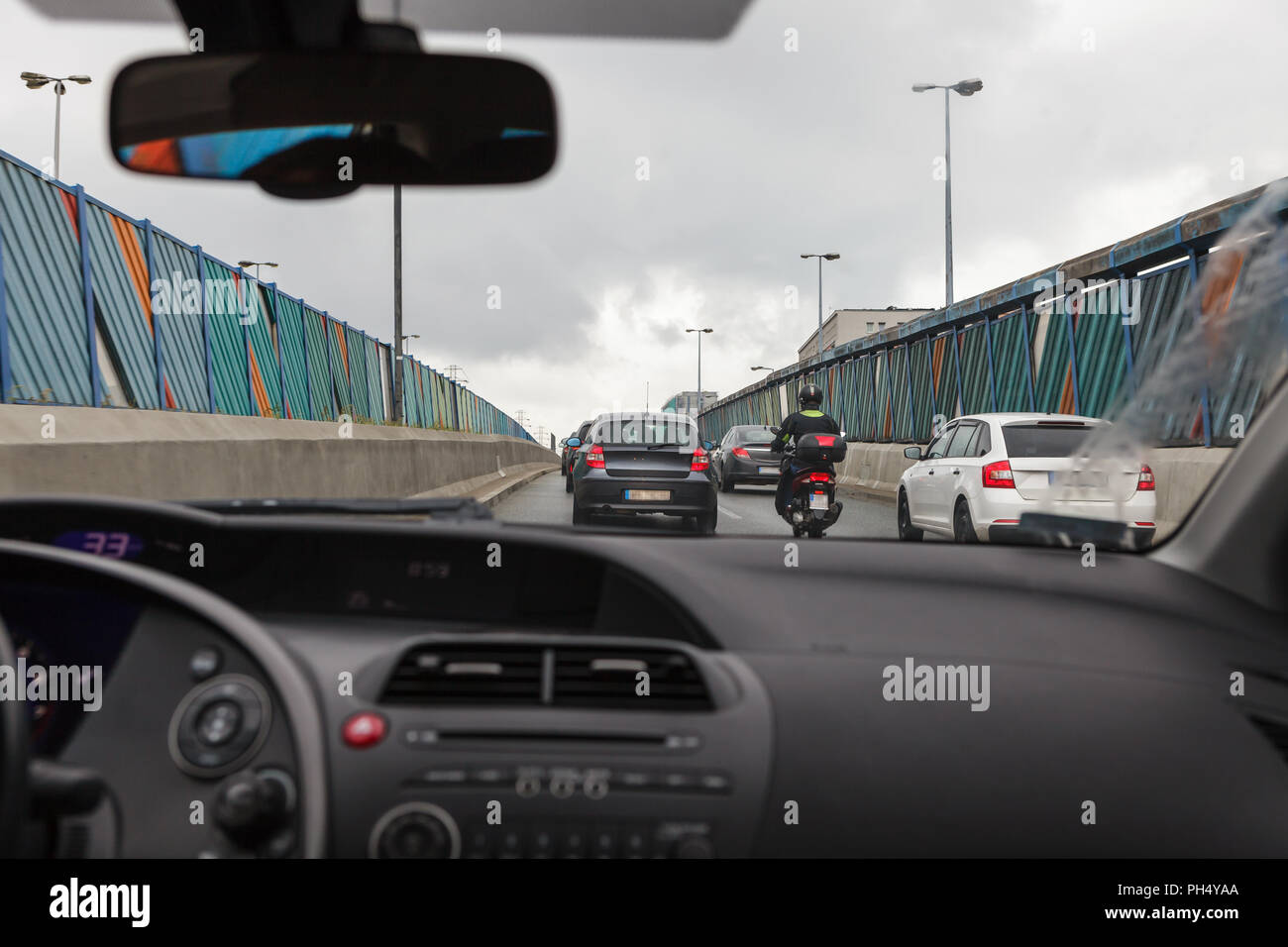 Alla guida di una autovettura in un ingorgo, vista dall'interno sulla strada affollata Foto Stock