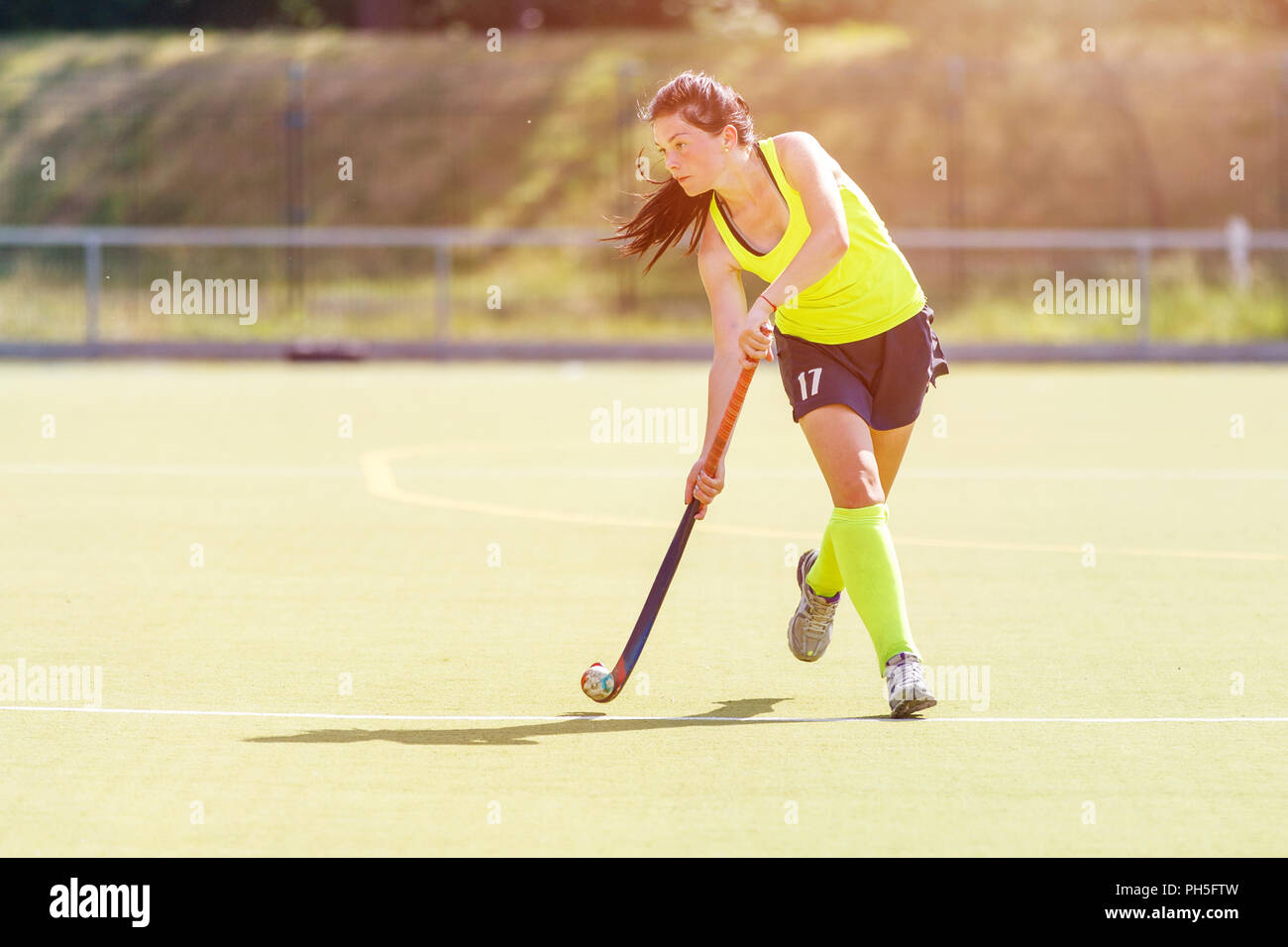 Giovane giocatore di hockey donna con sfera in attacco playing field hockey gioco Foto Stock