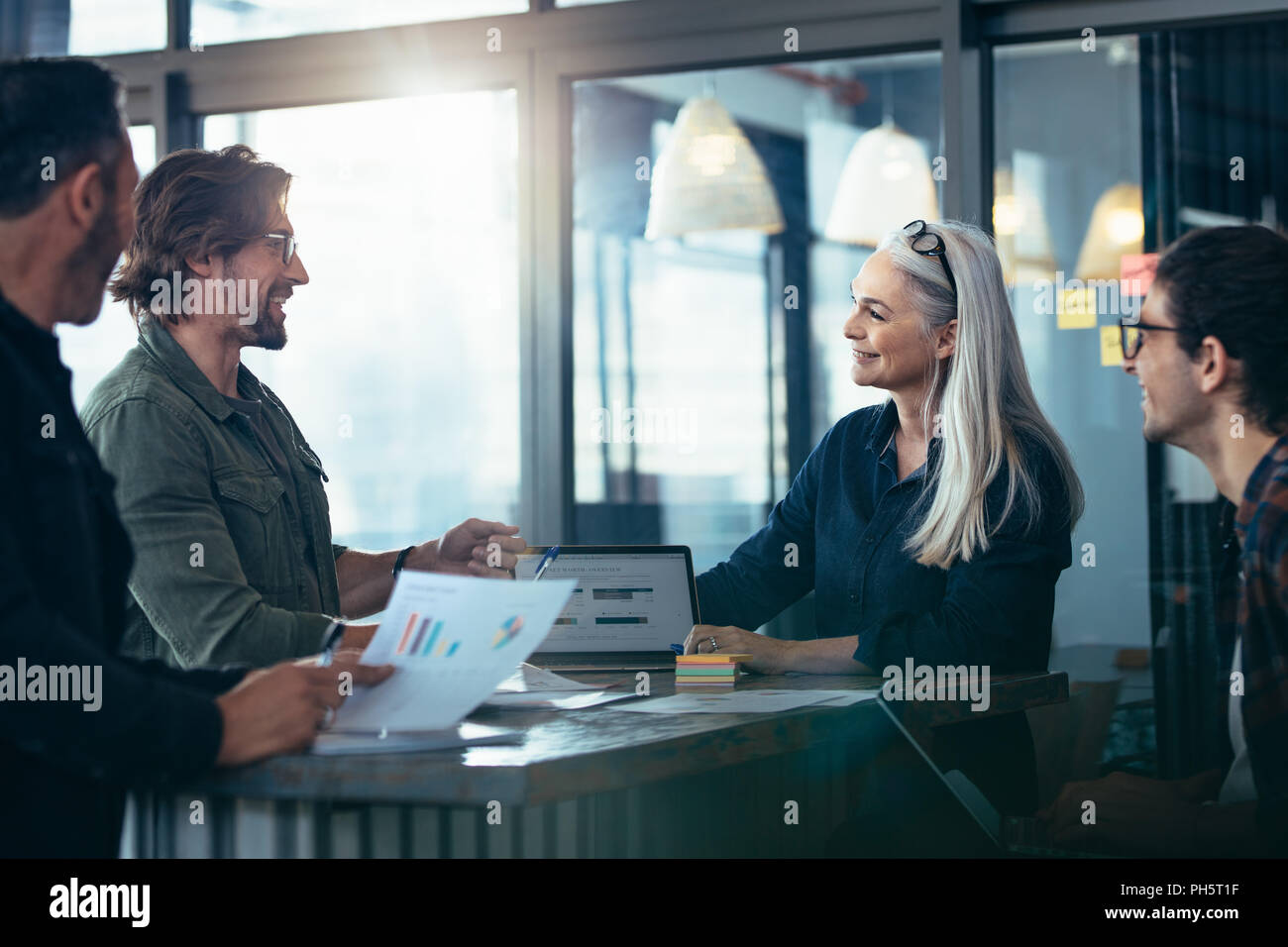 Un gruppo di persone di affari riuniti attorno a un tavolo. Il brainstorming su nuove idee di business. Il team di Business con grafici riunione in ufficio. Foto Stock