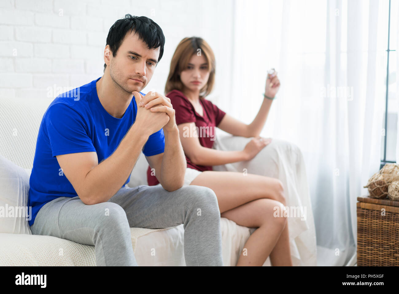 Frustrato marito uomo seduto accanto alla moglie cercando in test di gravidanza in mano moglie. Non è una buona notizia in mattinata Foto Stock