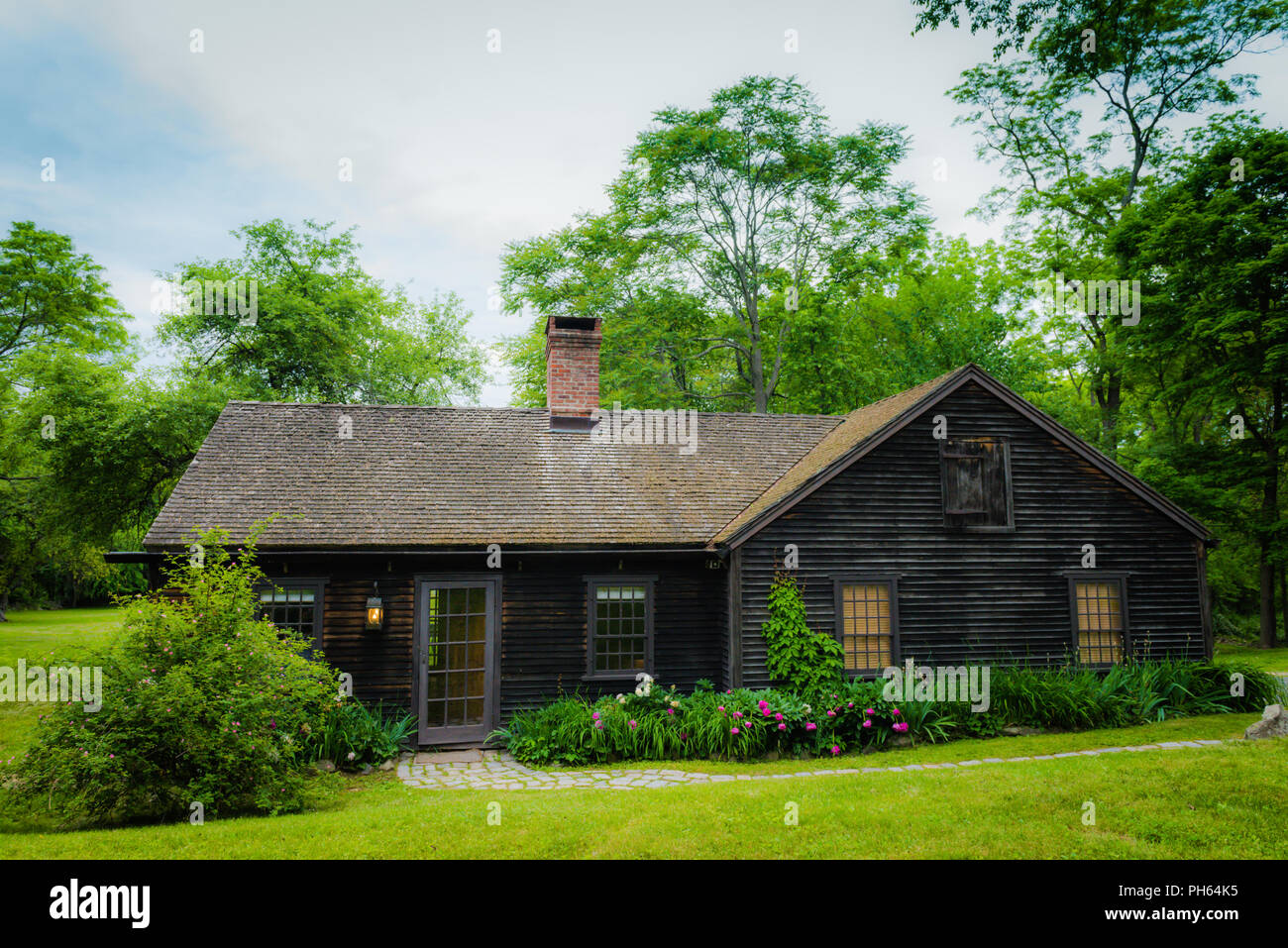 Un cottage di legno circondato da frontiere perenne e alberi di alto fusto in Upstate New York. Foto Stock