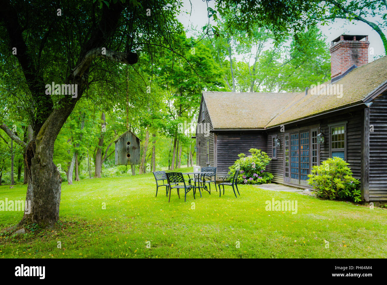 Un cottage di legno circondato da frontiere perenne e alberi di alto fusto in Upstate New York. Foto Stock