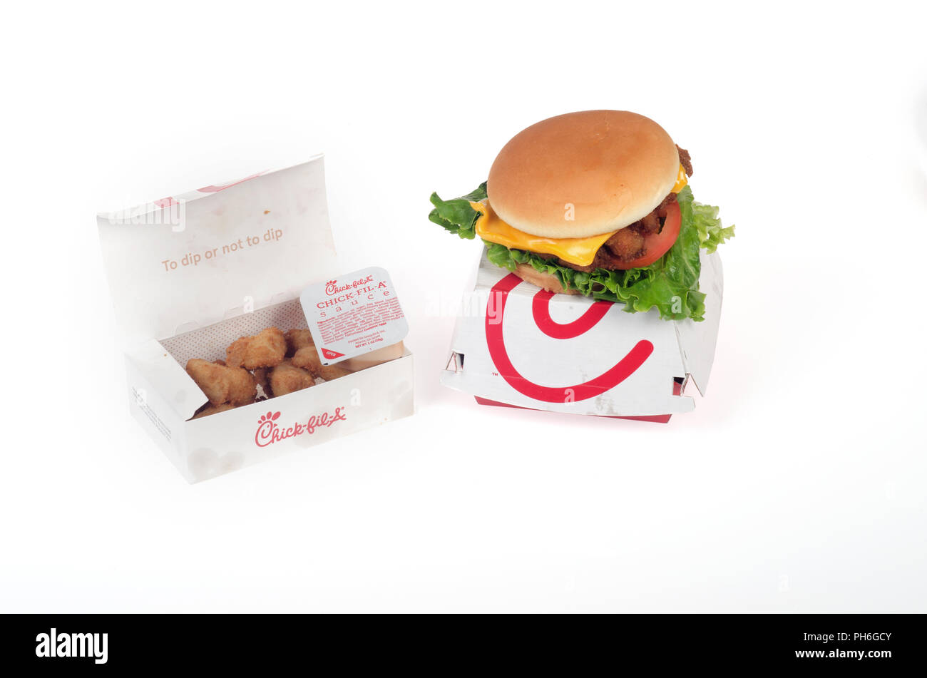 Chick-Fil-una Deluxe sandwich di pollo con lattuga, pomodoro e formaggio su un panino sulla parte superiore della confezione e una scatola di pepite di pollo con salsa di immersione su w Foto Stock