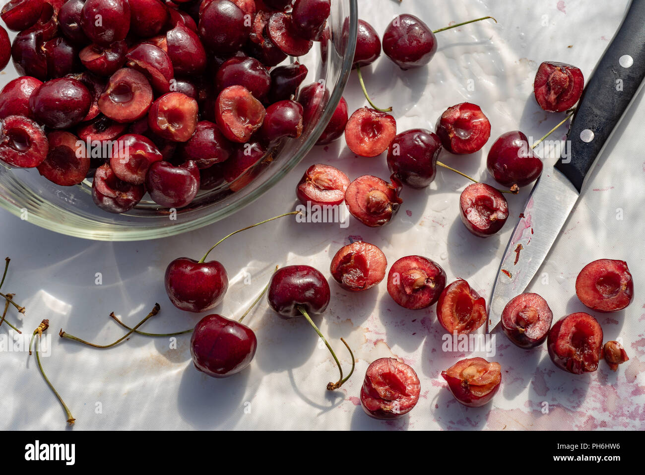 Fresche ciliege rosse tagliate a metà su bianco tagliere cucina still life Foto Stock