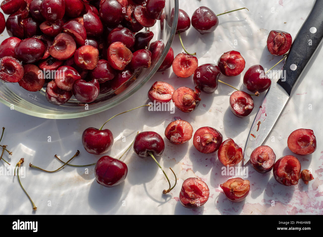 Fresche ciliege rosse tagliate a metà su bianco tagliere cucina still life Foto Stock