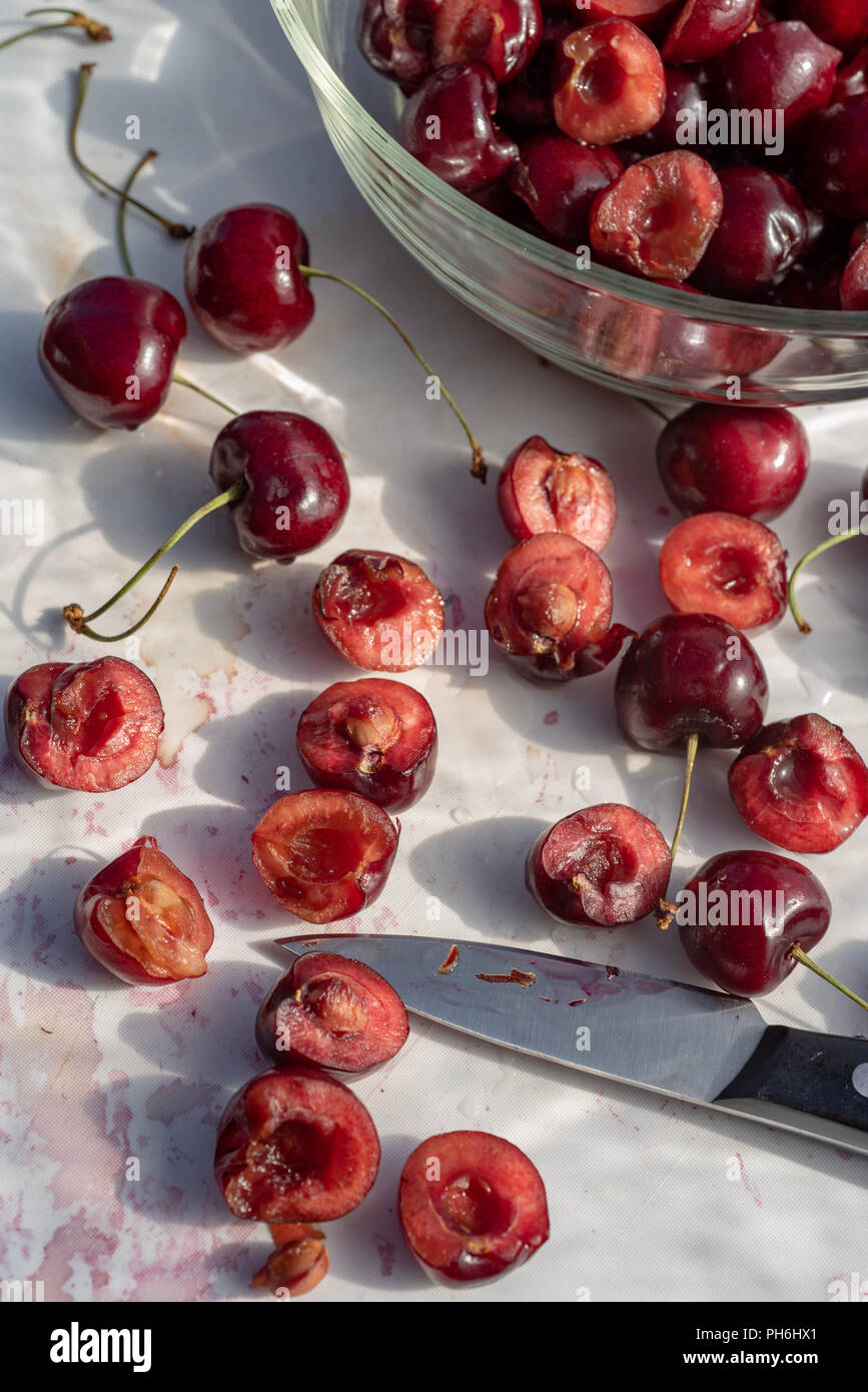 Fresche ciliege rosse tagliate a metà su bianco tagliere cucina still life Foto Stock