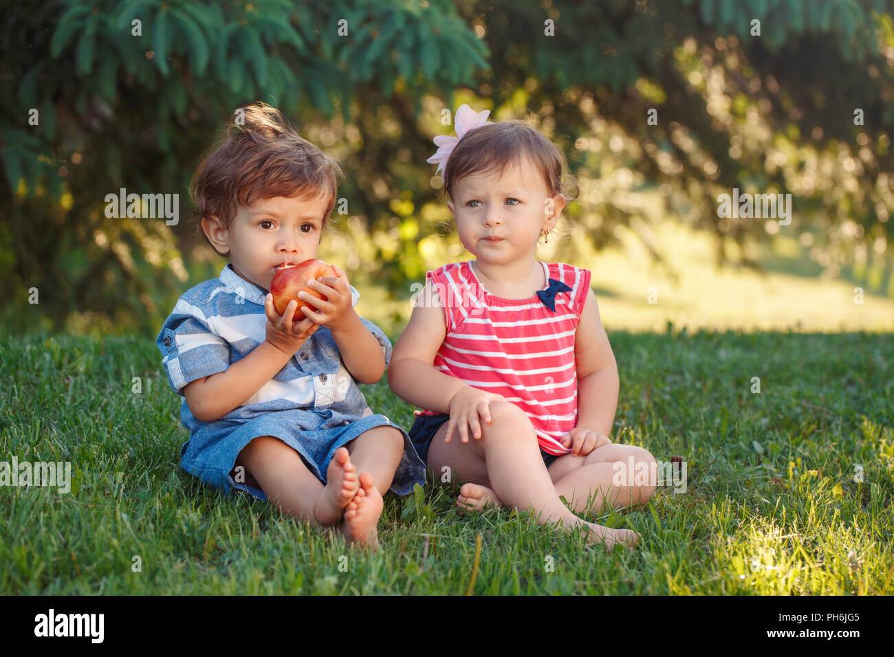 Ritratto di gruppo di due white Caucasian carino divertente adorabili bambini bambini seduti insieme condividendo cibo apple. Invidia amicizia concetto di infanzia. Essere Foto Stock