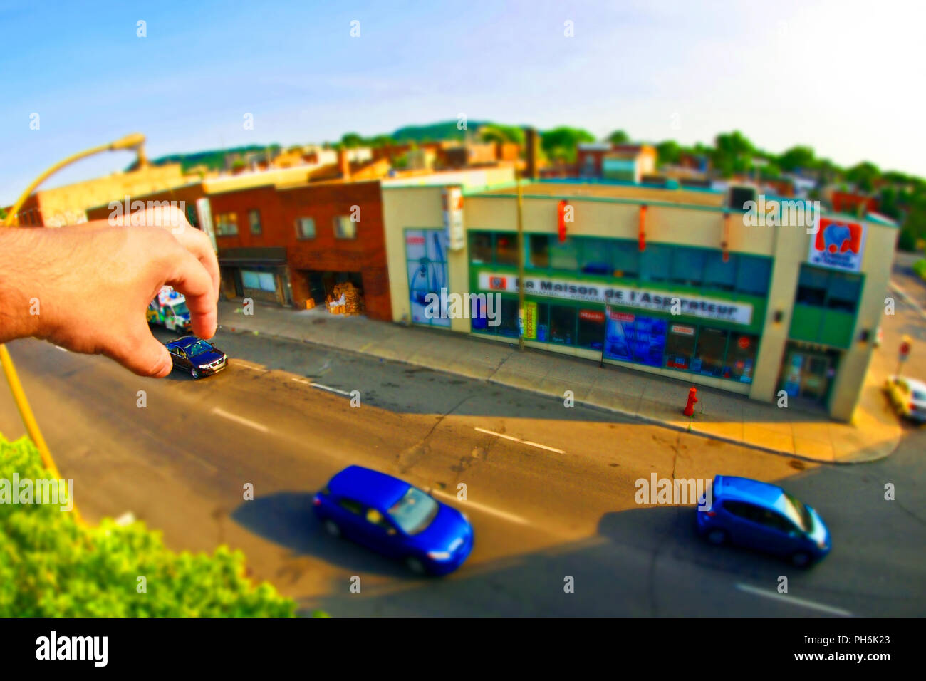 Foto di strada mani di Dio takin un auto blu diorama effetti speciali prospettiva shot giocattoli divertenti foto divertenti effetti in miniatura per effetto Foto Stock