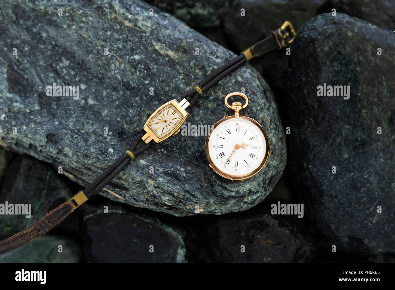 Set di orologi su bagnato pietre verdi con un classico oro orologio da  tasca e un orologio da polso con usura cinghie in pelle Foto stock - Alamy
