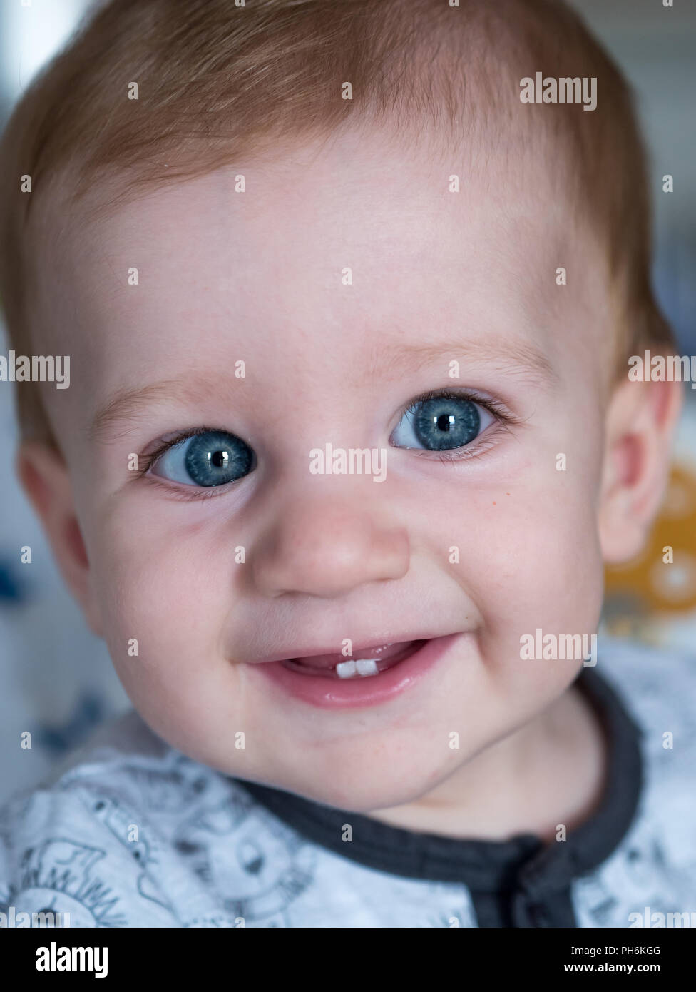 Carino redhead baby boy con gli occhi blu e due denti sorridente Foto Stock