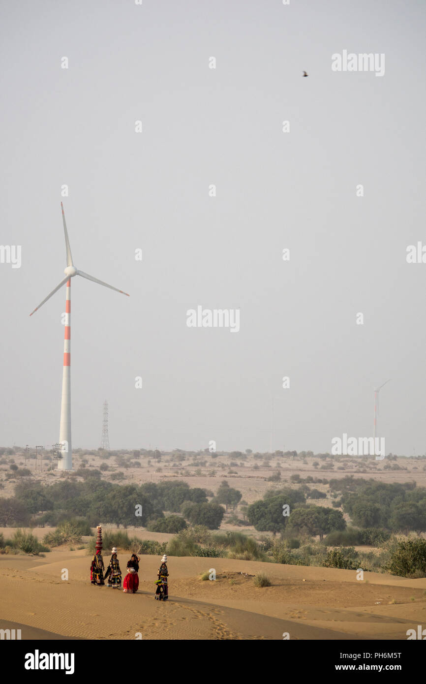 Le donne nomadi del deserto di Thar con turbina eolica in background, Rajasthan, India Foto Stock