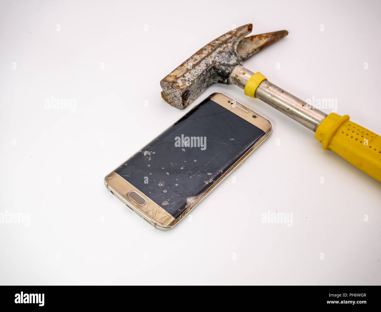 Danneggiato del display dello smartphone con il martello accanto ad esso Foto Stock