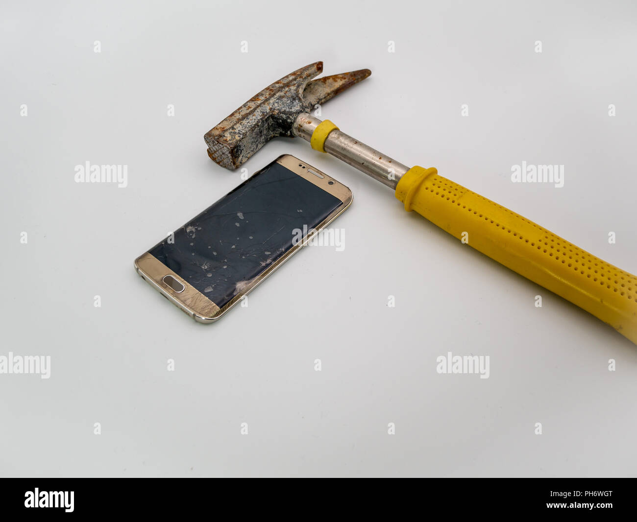 Danneggiato del display dello smartphone con il martello accanto ad esso Foto Stock