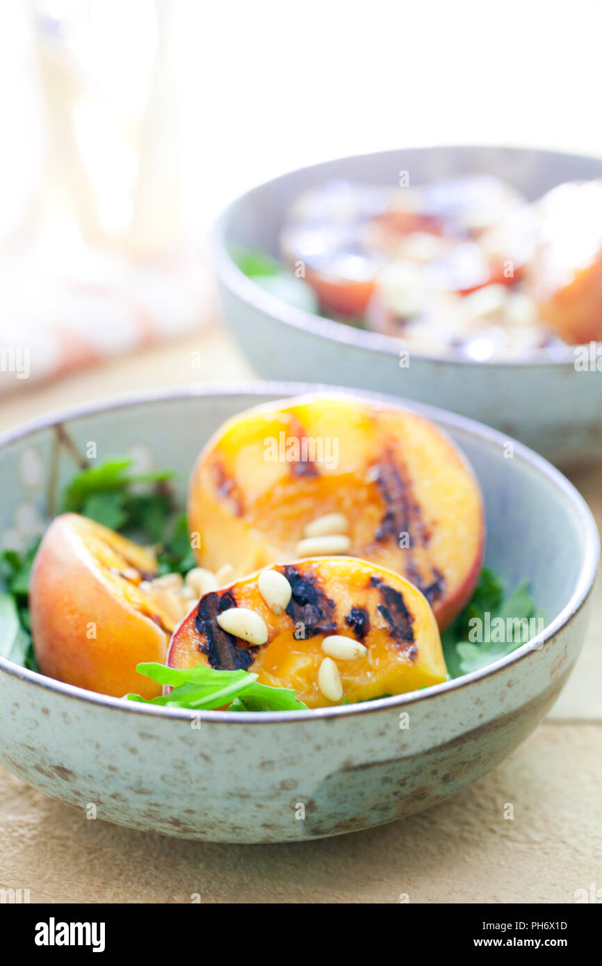 Grigliata di pesche, pinoli e rucola in ciotole Foto Stock