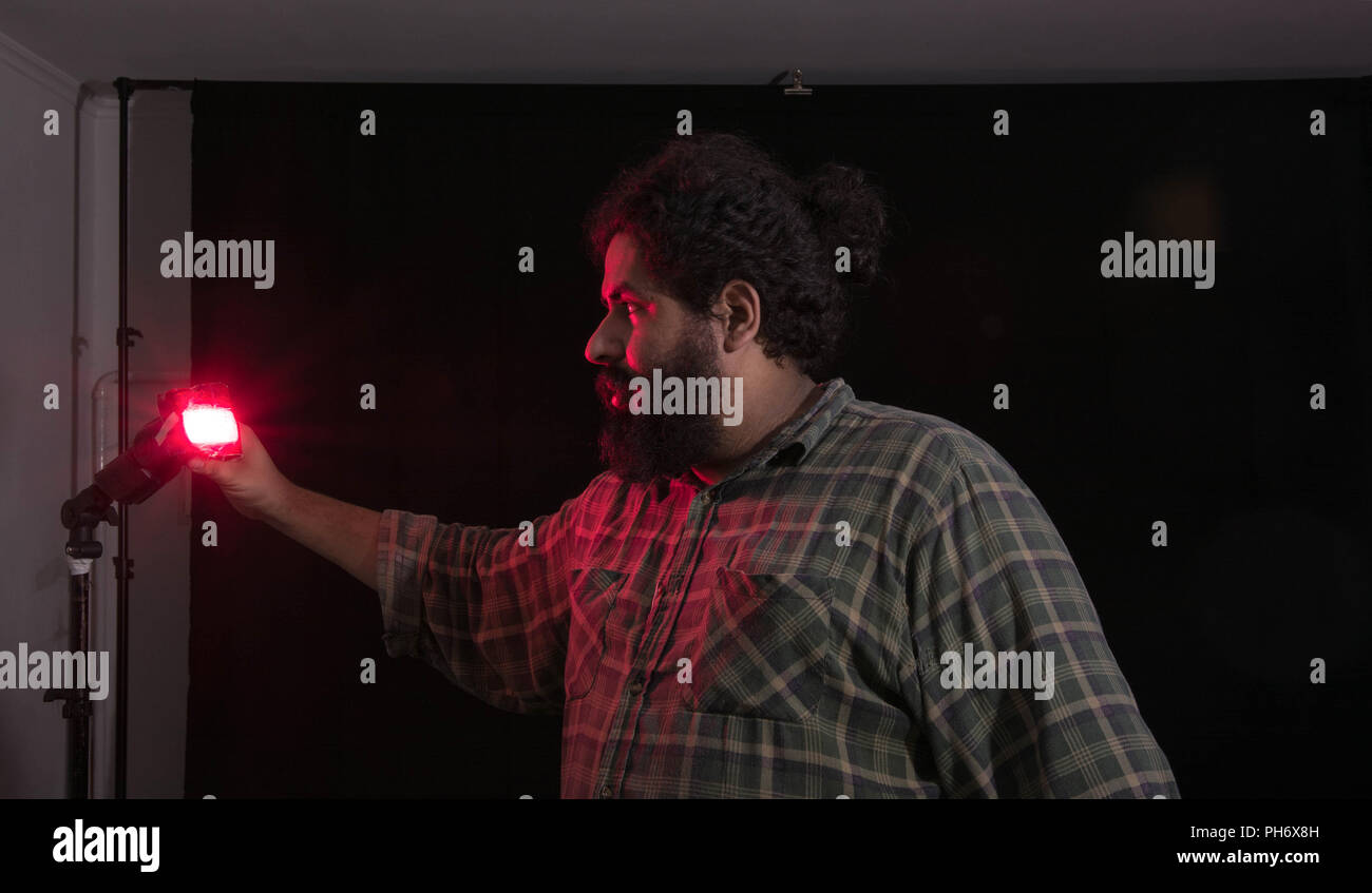 Grande uomo barbuto regolazione del flash in un studio fotografico Foto Stock