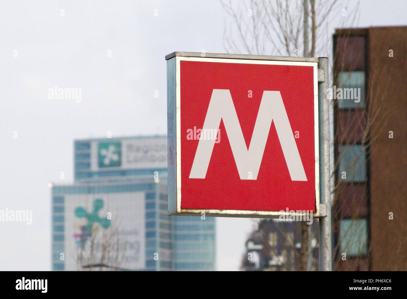 Milano, Italia. 2018/8/2. Una 'M' segno di una stazione della metropolitana. Grattacieli in background. Foto Stock