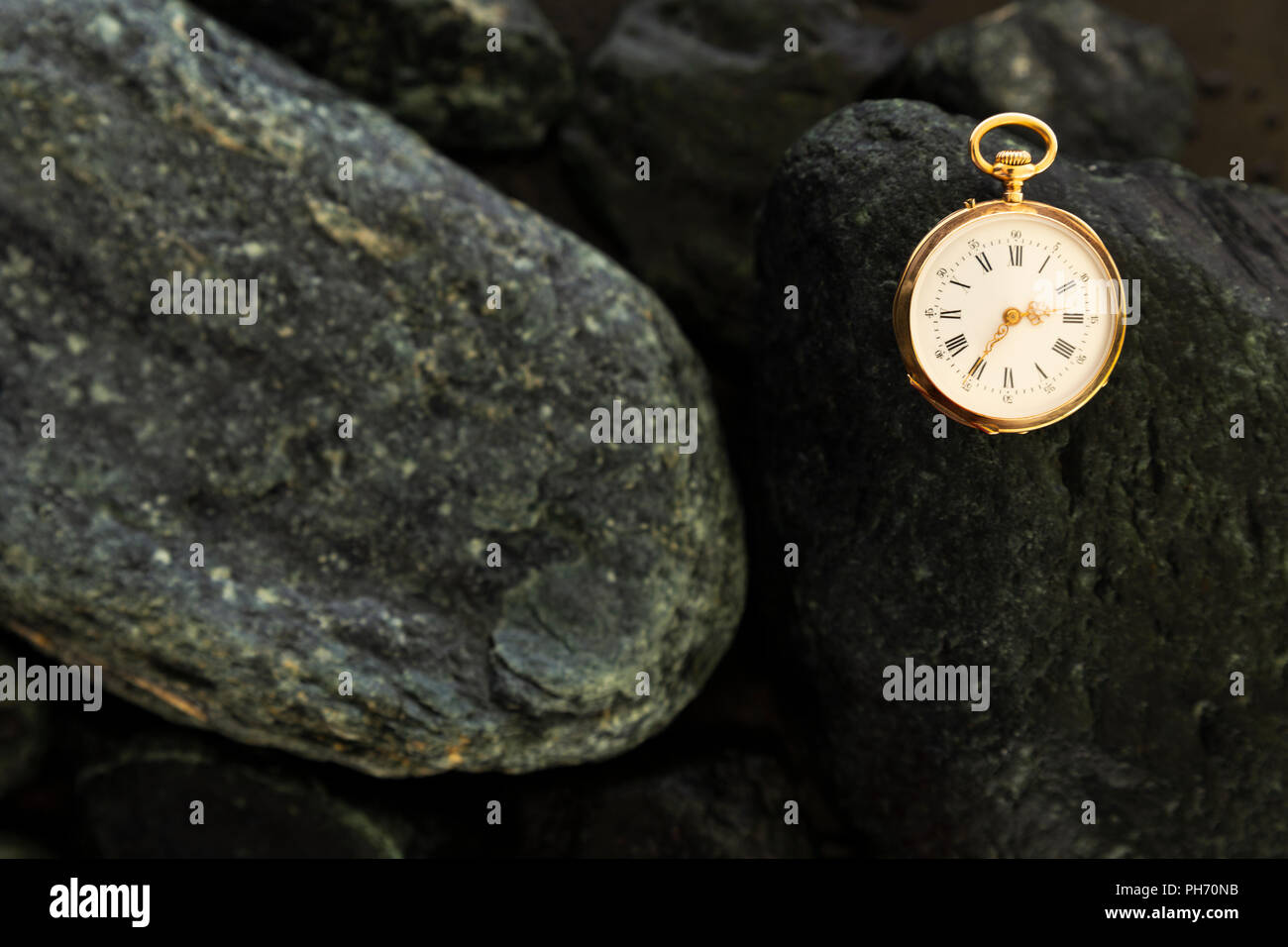 Primo piano di un bellissimo oro classico orologio da tasca la posa su bagnato pietre verdi Foto Stock