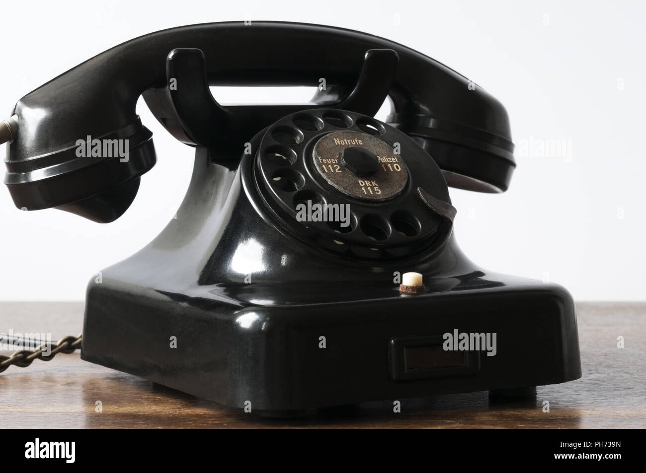 Vecchio telefono nero su una scrivania e sfondo bianco. Foto Stock