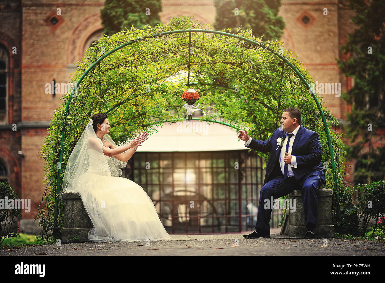 Coppie in viaggio di nozze sfondo verde arco della pianta. Bouquet su aria Foto Stock