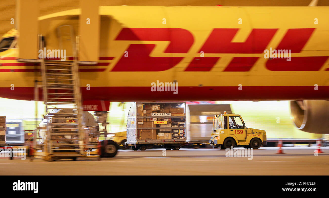 29.08.2018 Sassonia, Schkeuditz: un trattore tira i rimorchi con i container per il trasporto merci su Lipsia/Halle aeroporto di notte. Il mozzo di DHL a Leipzig Airport entrò in funzione dieci anni fa. A quel tempo, 125.000 spedizioni sono state gestite al giorno in media, oggi è 350.000. Il mozzo di Lipsia ha sviluppato nel più grande all'interno del network DHL Express in dieci anni. Nel frattempo 5700 persone lavorano presso la posizione, 99 percento di essi dalla regione. In aggiunta ai cinque nuovi aeromobili, DHL è la pianificazione di un simulatore di volo per centro pilota di formazione e di addestramento. Foto: Jan Woitas/dpa-Zentralbild/d Foto Stock