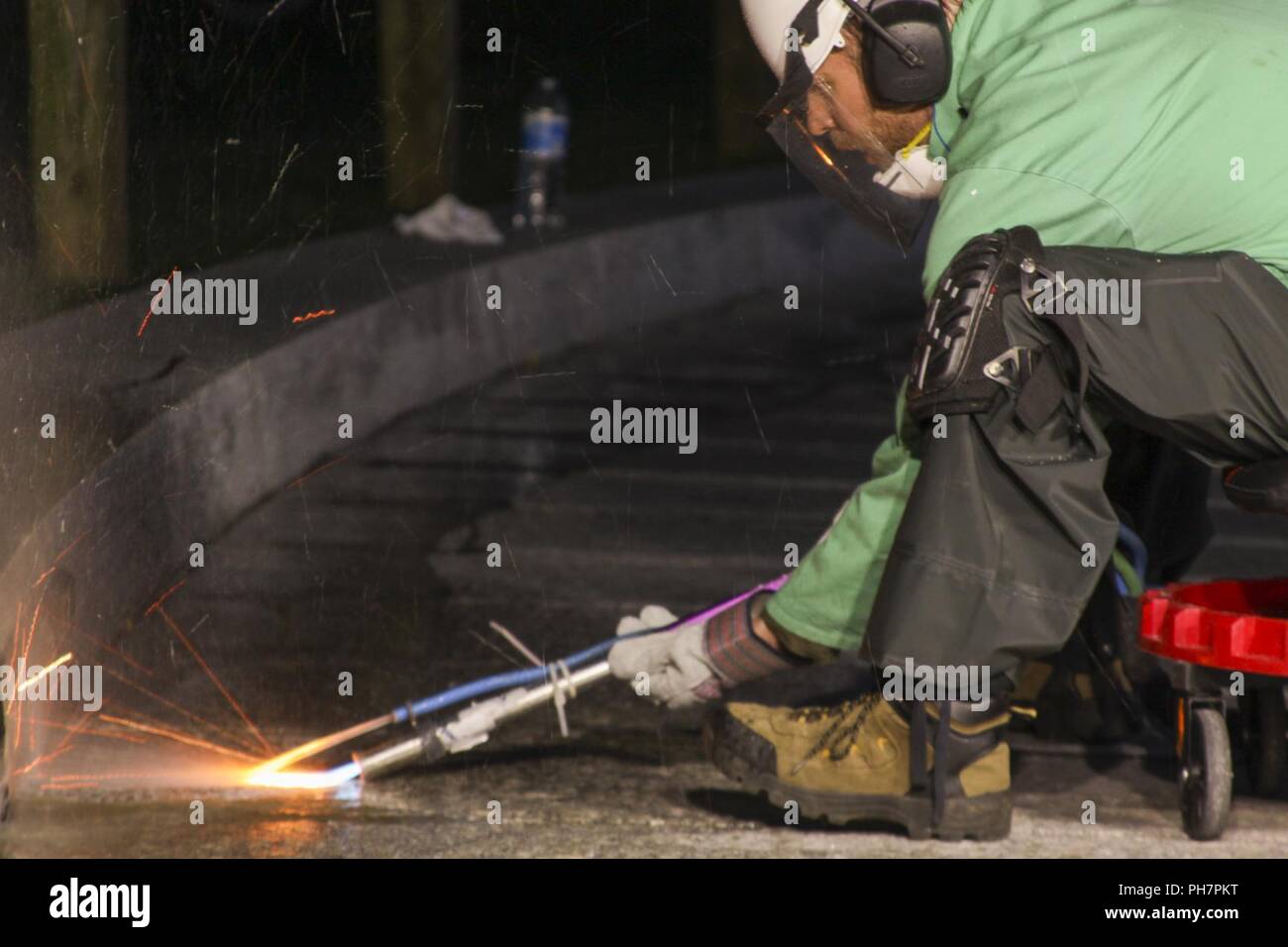 (Il Cimitero Nazionale di Arlington) - Gli appaltatori che lavorano per gli Stati Uniti Esercito di ingegneri del distretto di Norfolk, utilizzare uno speciale trattamento alla fiamma per rodare il granito passaggi pedonali che conducono al Presidente John F. Kennedy luogo di sepoltura qui Giugno 22, 2018. La passerella viene spianata per renderlo meno scivoloso quando è bagnato, rendendola più sicura per i visitatori del cimitero. Foto Stock