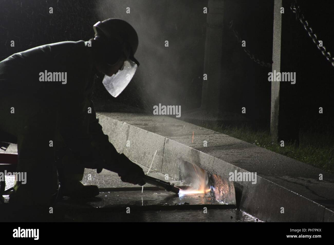 (Il Cimitero Nazionale di Arlington) - Gli appaltatori che lavorano per gli Stati Uniti Esercito di ingegneri del distretto di Norfolk, utilizzare uno speciale trattamento alla fiamma per rodare il granito passaggi pedonali che conducono al Presidente John F. Kennedy luogo di sepoltura qui Giugno 22, 2018. La passerella viene spianata per renderlo meno scivoloso quando è bagnato, rendendola più sicura per i visitatori del cimitero. Foto Stock