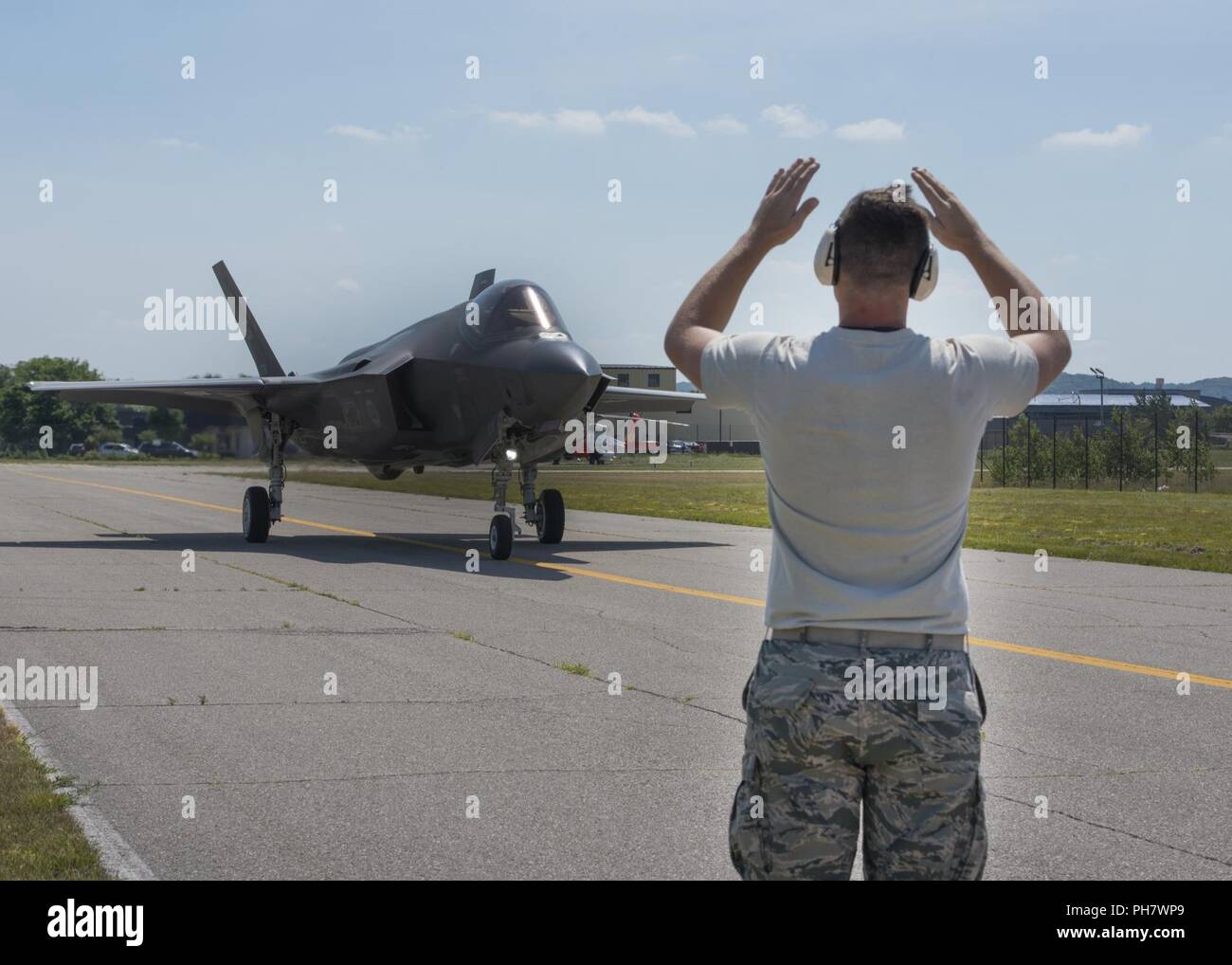 Stati Uniti Air Force Staff Sgt. Ryan Littlejohn, xxxiii Fighter Wing sistemi avionici artigiano, esegue il marshalling di un F-35un fulmine II Giugno 29, 2018 a Traverse City, Mich Il National Sagra delle ciliegie Air Show ha accolto con favore il Navy Blue Angels team di dimostrazione presso la guardia costiera Stazione aria di Traverse City, Mich e presentato una rampa aperta la visualizzazione statica di diversi aerei. Foto Stock