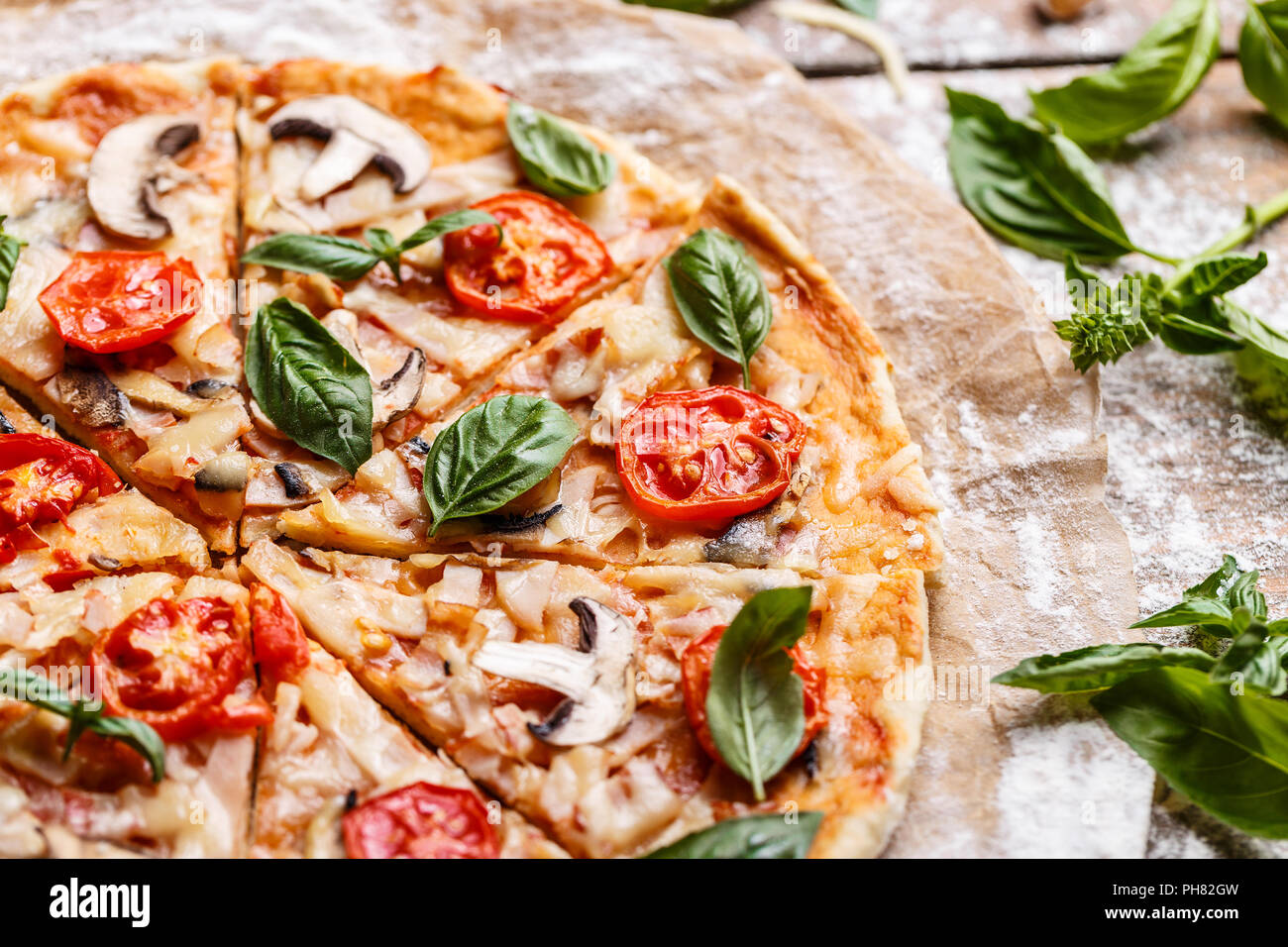 Composizione di una gustosa pizza decorato con foglie di basilico Foto Stock