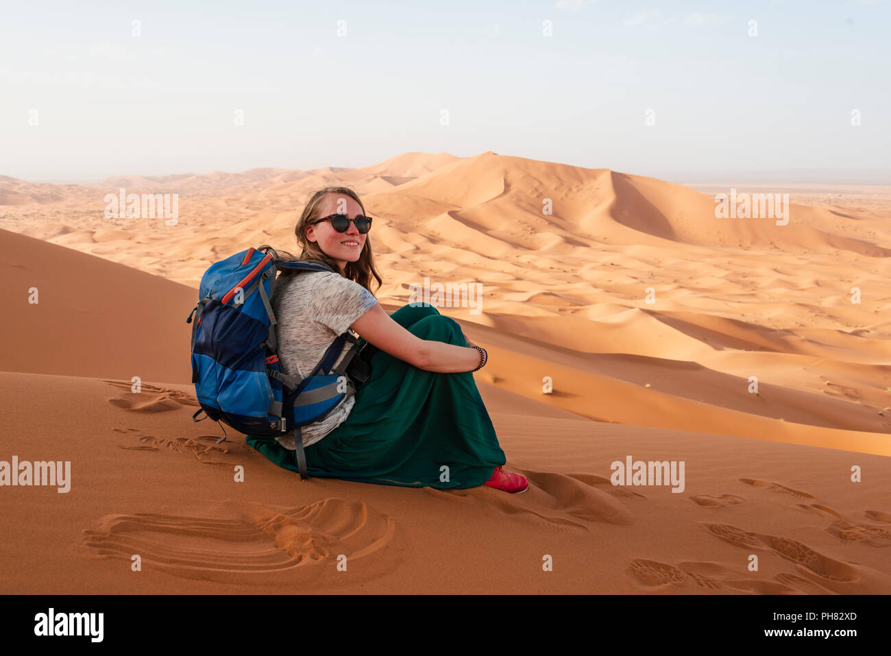 Escursionista femmina su una rossa duna di sabbia nel deserto, paesaggio di dune Erg Chebbi, Merzouga, Sahara, Marocco Foto Stock