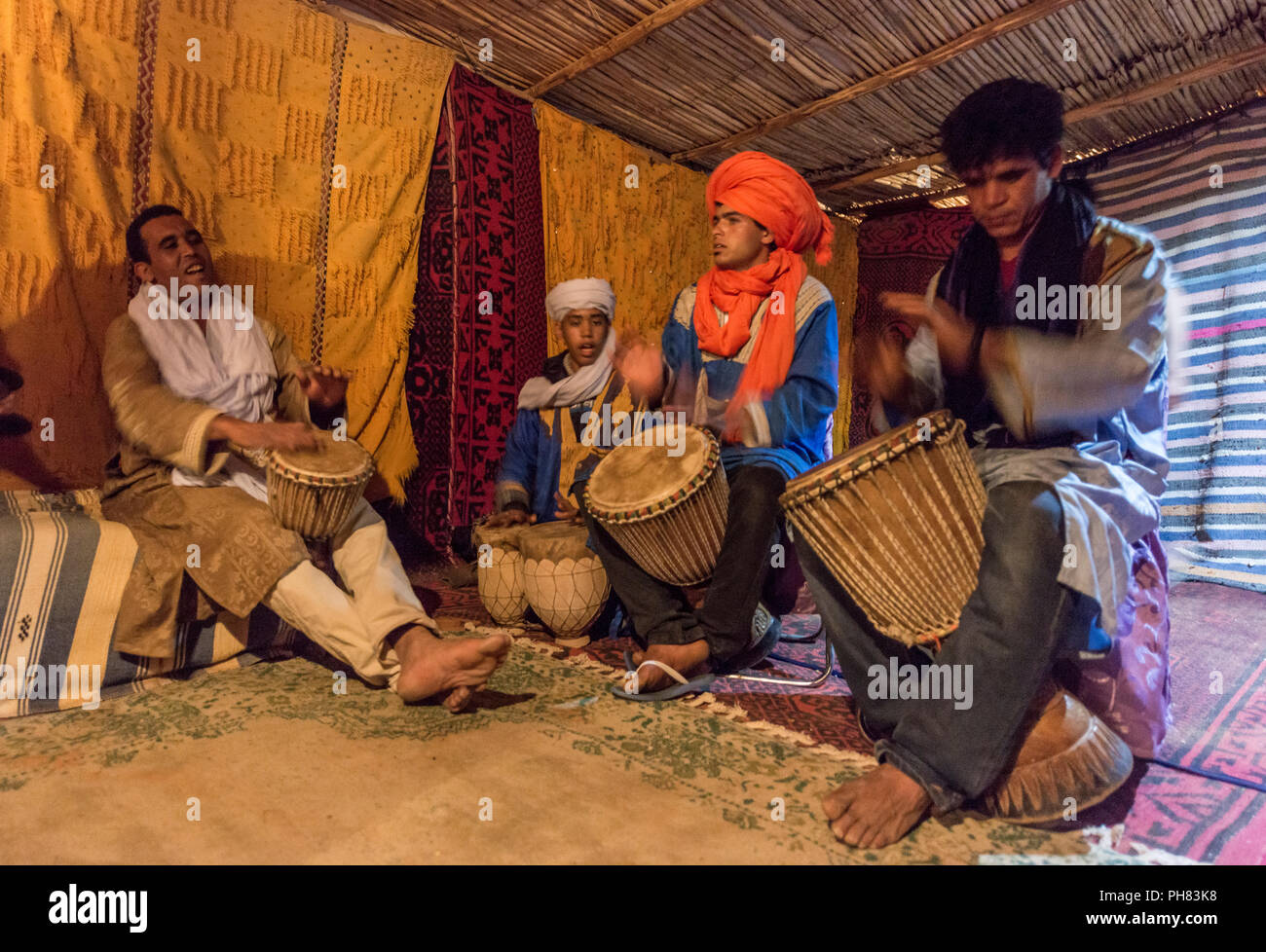 I beduini con abiti tradizionali giocare su tamburi in una tenda, Erg Chebbi, Merzouga, Sahara, Marocco Foto Stock