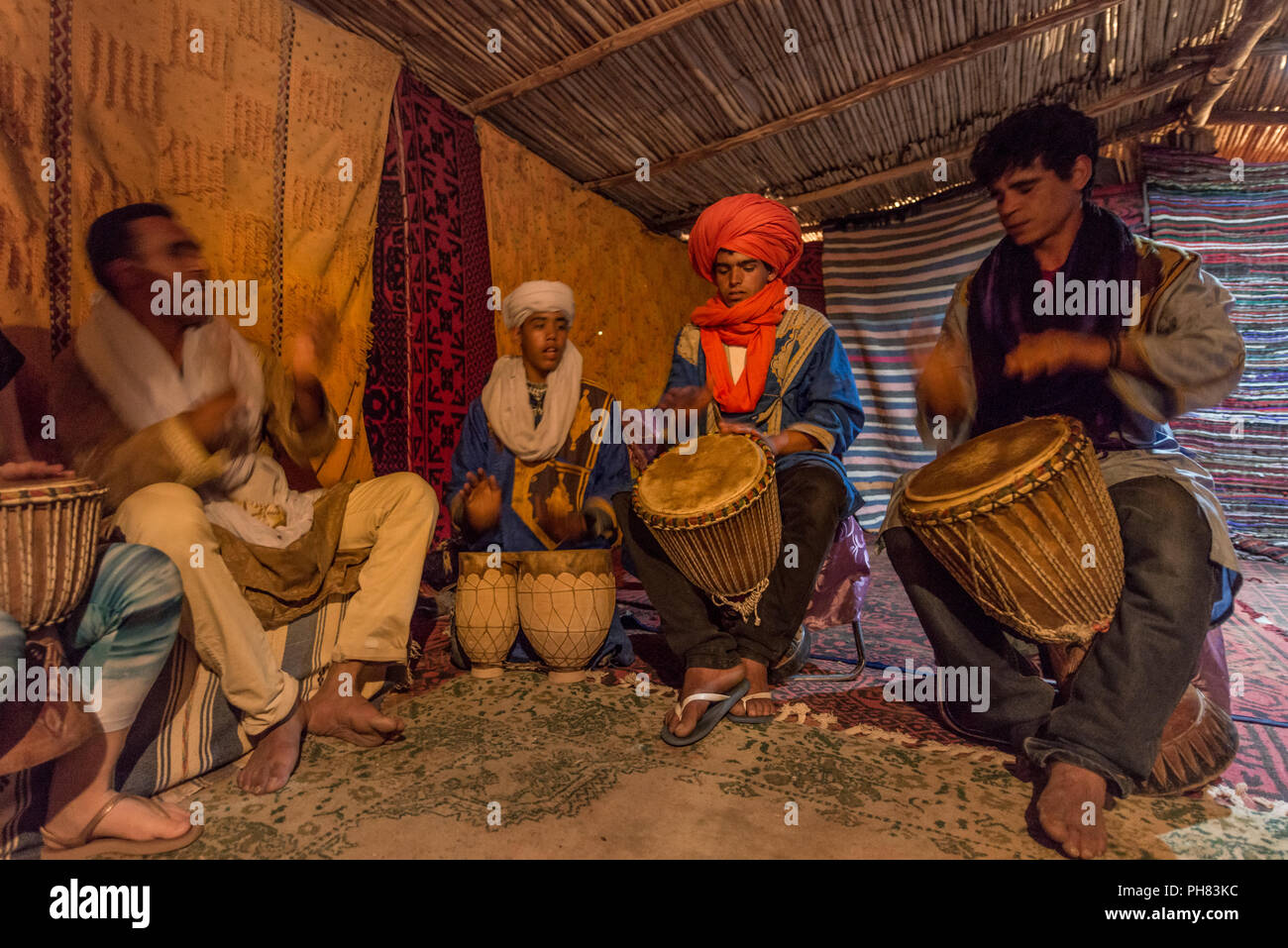 I beduini con abiti tradizionali giocare su tamburi in una tenda, Erg Chebbi, Merzouga, Sahara, Marocco Foto Stock