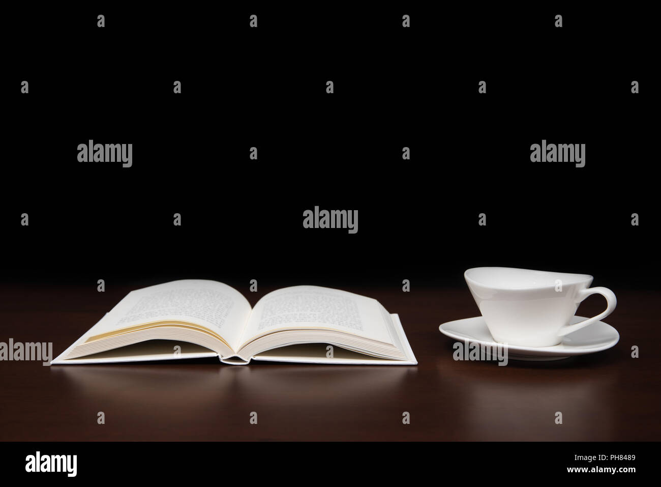 Un libro aperto sulla scrivania con una tazza di caffè. Foto Stock