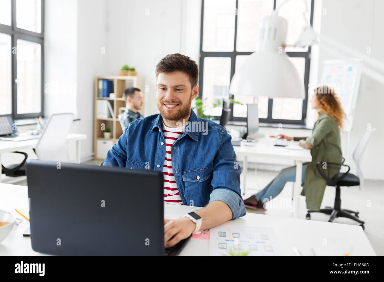Sorridente uomo creativo con il computer portatile lavorando in ufficio Foto Stock