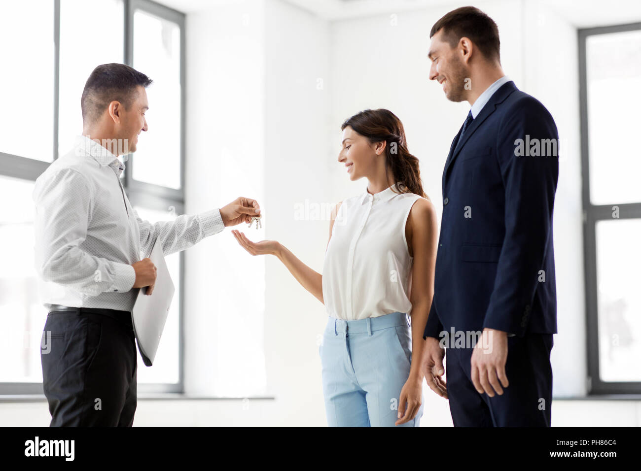 Agente immobiliare che dà la chiave per i clienti al nuovo ufficio Foto Stock