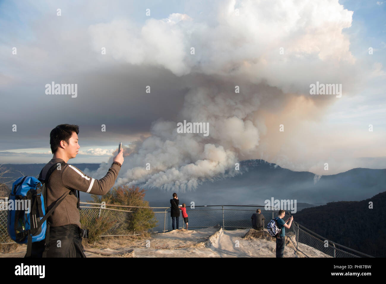 I turisti a guardare e fotografare un rischio di incendio la riduzione a monte solitario, Blue Mountains, Australia Foto Stock