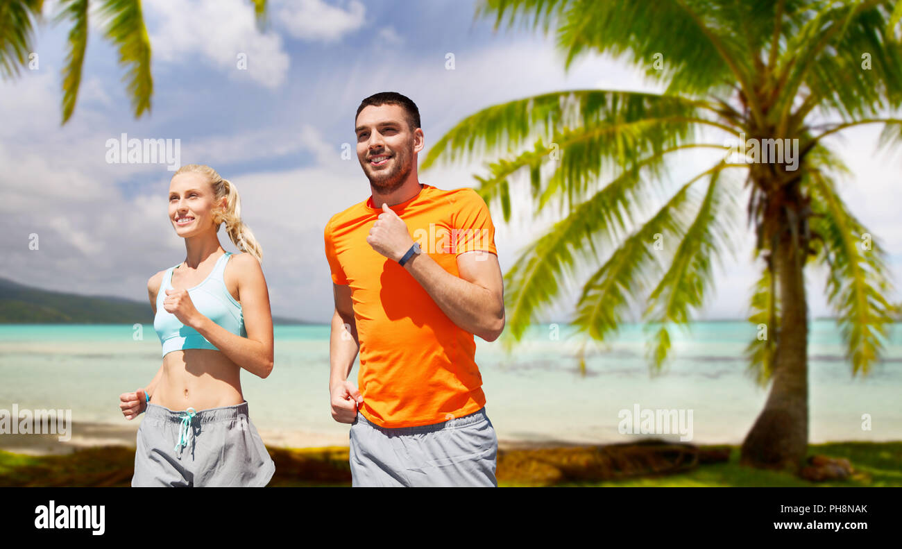 Coppia sorridente in esecuzione sulla spiaggia tropicale Foto Stock
